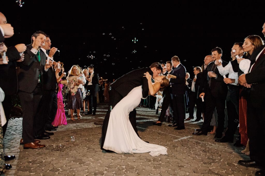 The bride and groom kissing while being blown bubbles