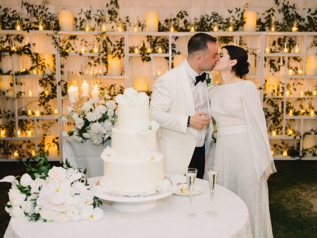 A couple kissing next to a cake