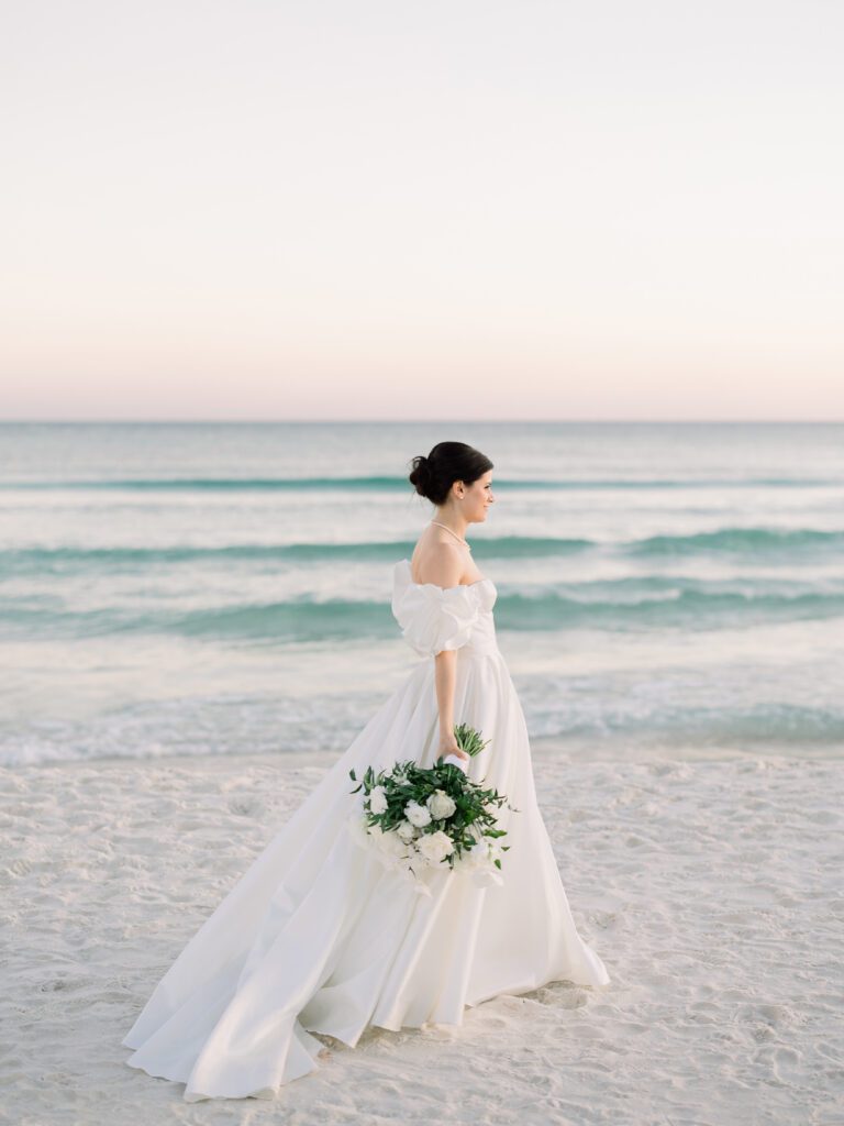 A woman with a white gown walking on a beach