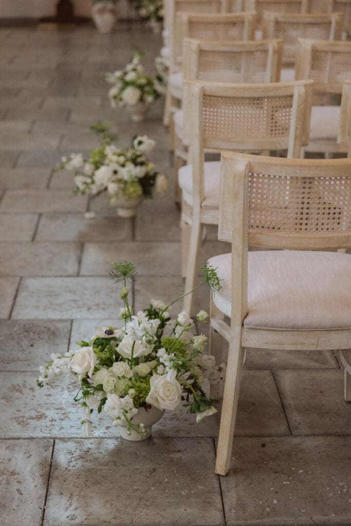 Floral arrangements beside wedding chairs